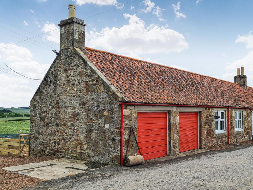 an old stone building with red garage doors at 2 Setonhill Cottages in Longniddry