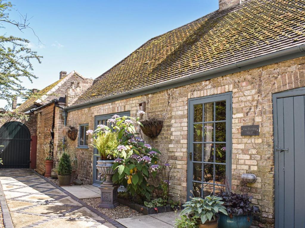 a brick house with flowers in a courtyard at The Potting Shed in Huntingdon