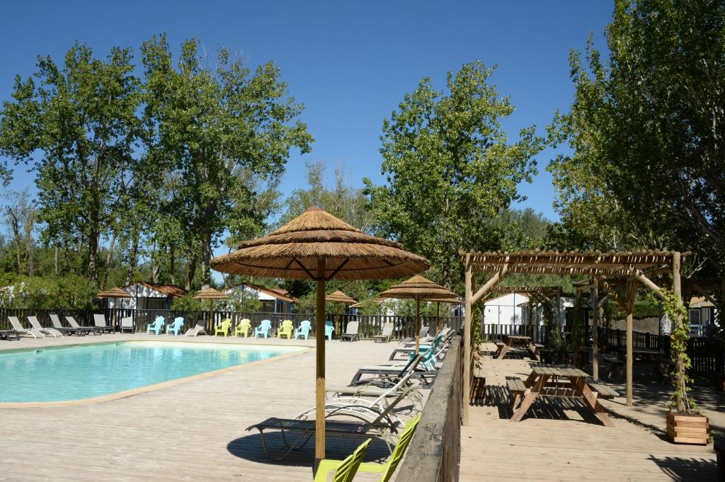 una piscina con sillas y sombrillas junto a una piscina en Camping La Dune en Vias