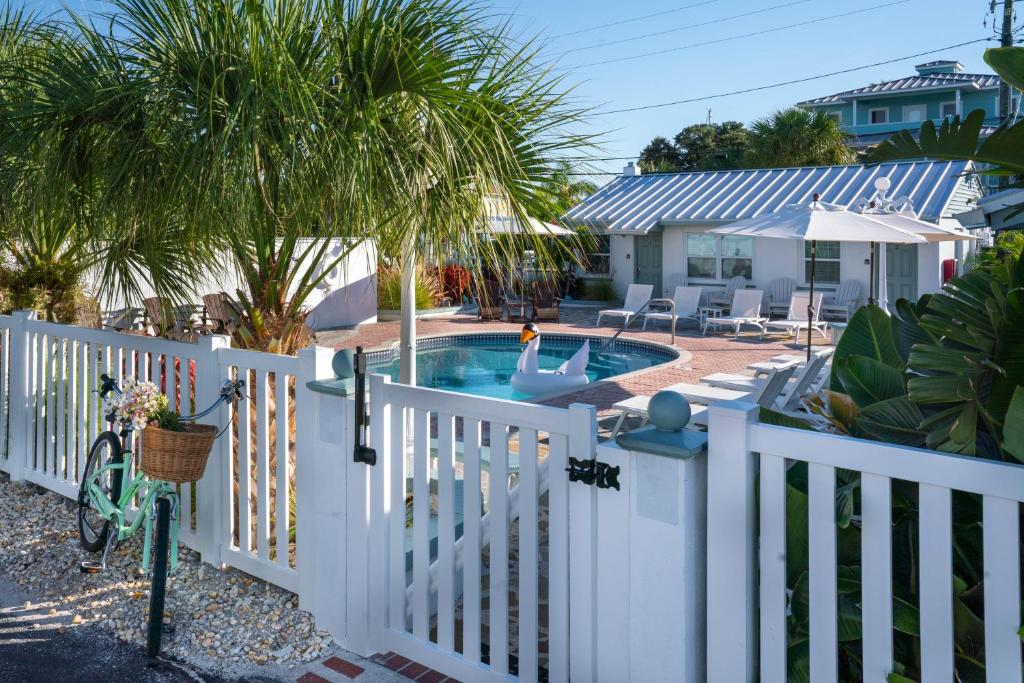 una recinzione bianca con una piscina in un cortile di The Bungalows a St Pete Beach