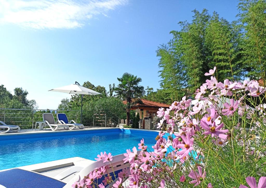 a swimming pool with purple flowers in front of it at Apartments Garden Residence in Opatija