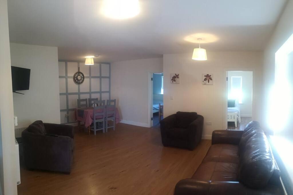 a living room with a leather couch and a dining room at Spacious and warm 2 bedroom apartment sleeps up to 5 in Athy