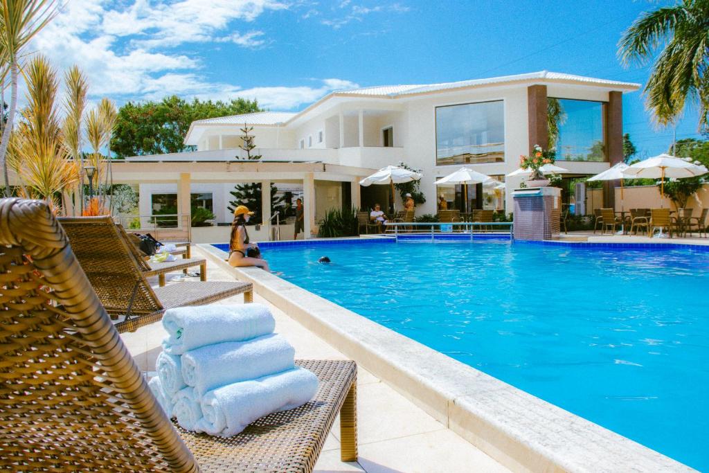 a villa with a swimming pool in front of a house at Pontal Praia Hotel in Porto Seguro