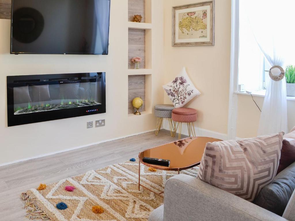 Cairnsmore - Uk34533 في نيوتن ستيوارت: غرفة معيشة مع أريكة وتلفزيون على الحائط