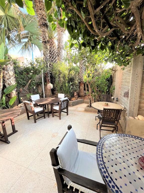 an outdoor patio with tables and chairs and trees at logis la marine in Sidi Ifni