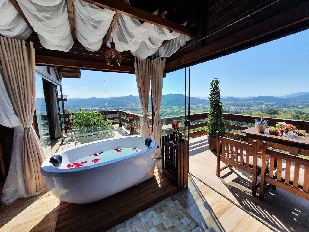 y baño con bañera en una terraza con vistas. en Chalé da Montanha com Ofurô en Santo Amaro da Imperatriz