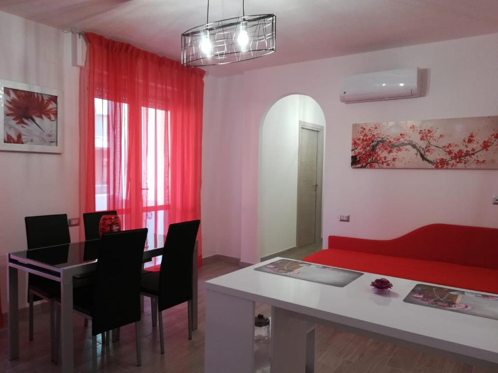 uma sala de estar com uma mesa e um sofá vermelho em Sweet Home QSE em Quartu SantʼElena