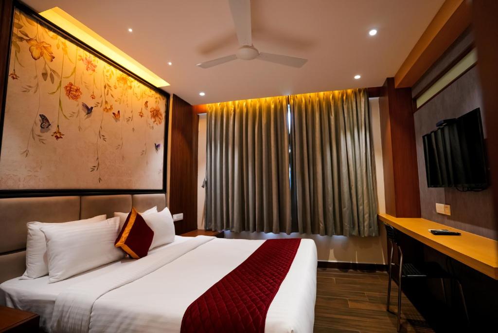 a bedroom with a large white bed and a desk at Eden Park Boutique Hotel in Vijayawāda