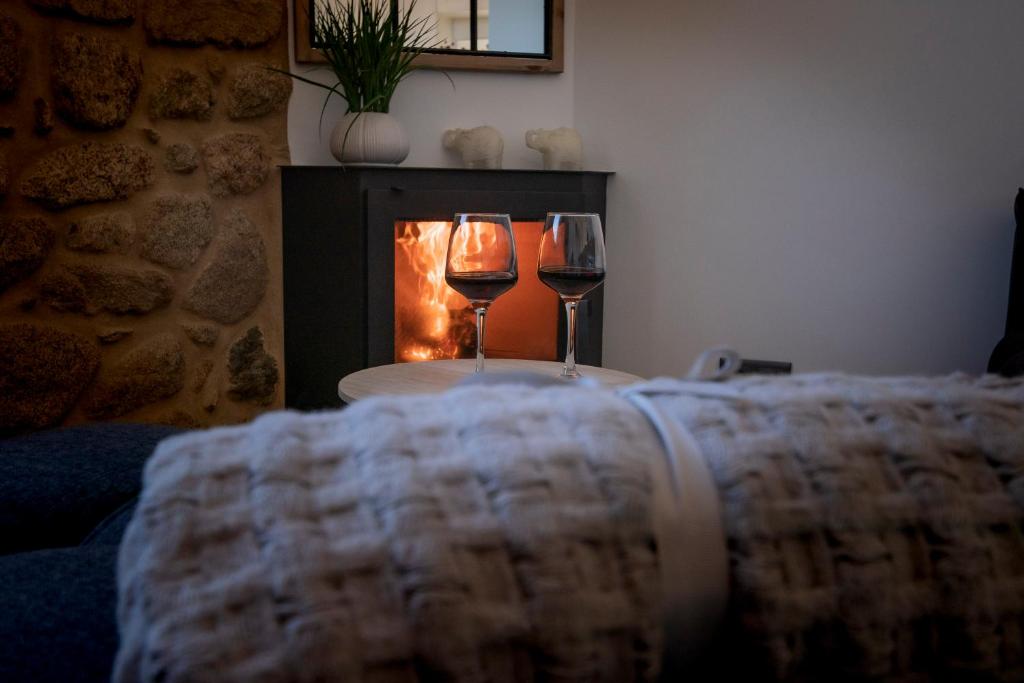 two wine glasses sitting on a table in front of a fireplace at Casa mirador Tía Amalia in Carnota