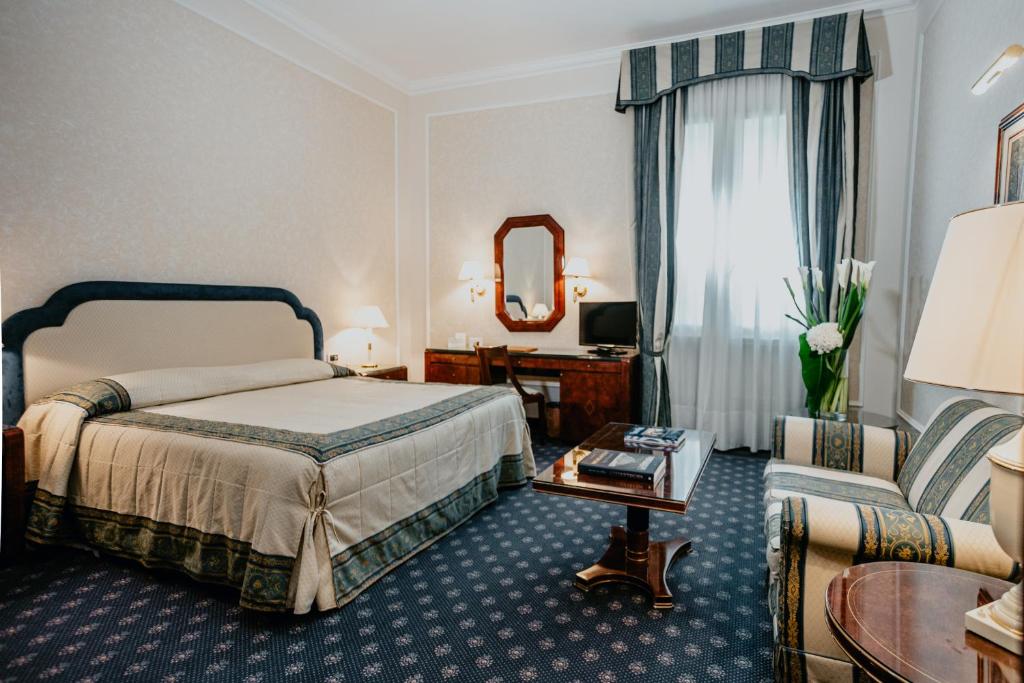 Pokój hotelowy z łóżkiem i lustrem w obiekcie Hotel De La Ville we Florencji