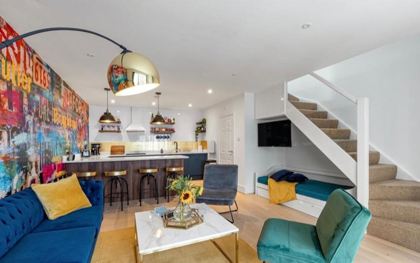 sala de estar con sofá azul y cocina en Mrs Butler’s Mews House en Brighton & Hove