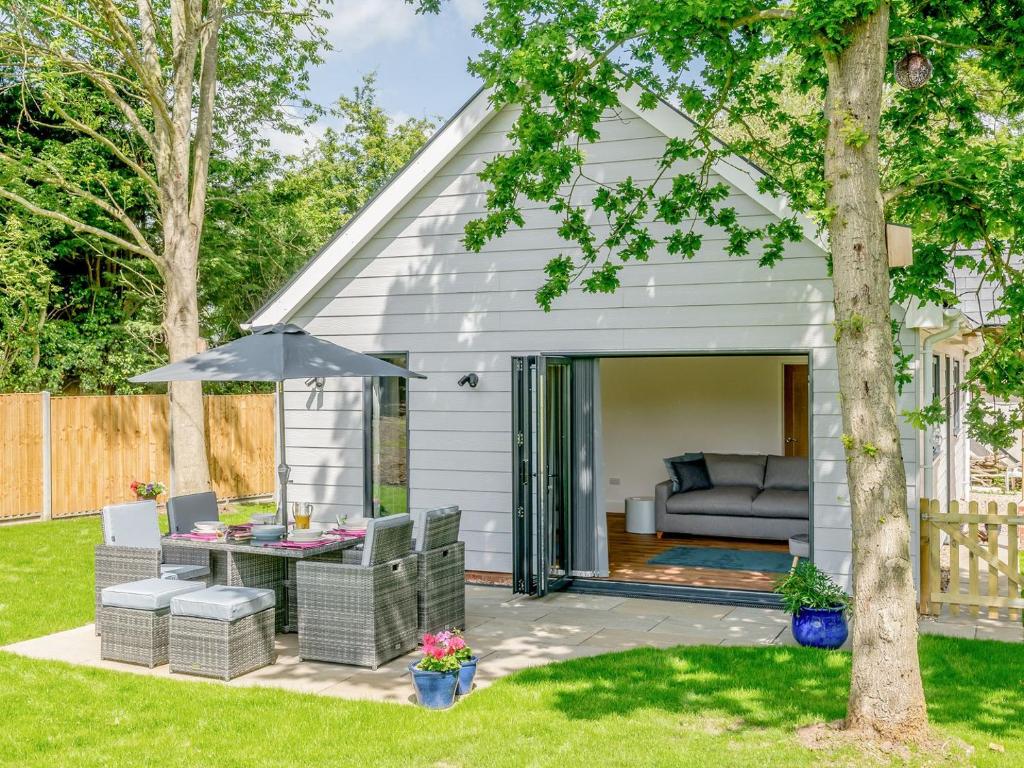 a backyard patio with a couch and an umbrella at Willow Cottage in Stonham Aspall