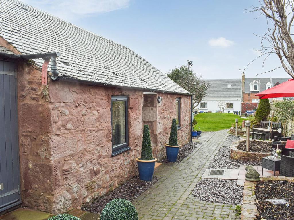 una casa de piedra con árboles delante de ella en The Cottage, en Girvan