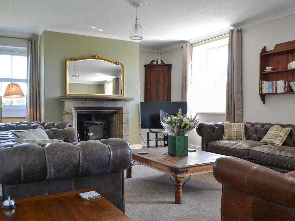 a living room with couches and a table and a mirror at Fieldside Farmhouse in Tallentire