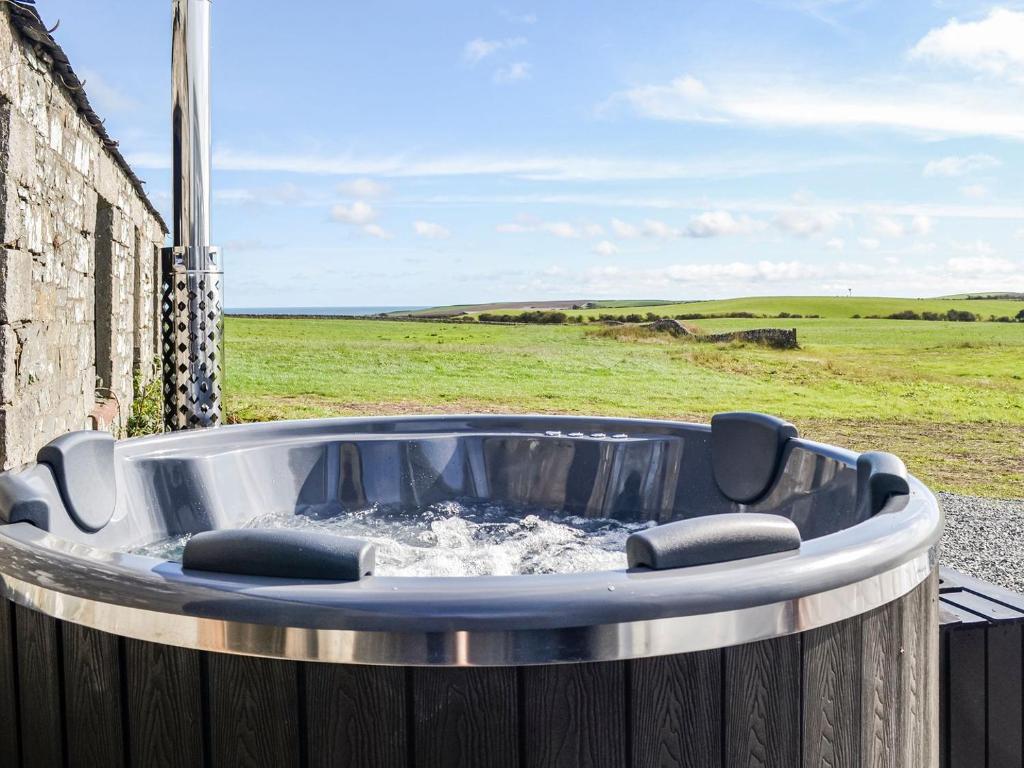 a jacuzzi tub with a field in the background at The Seaview Retreat - Uk35883 in Broughton Mains