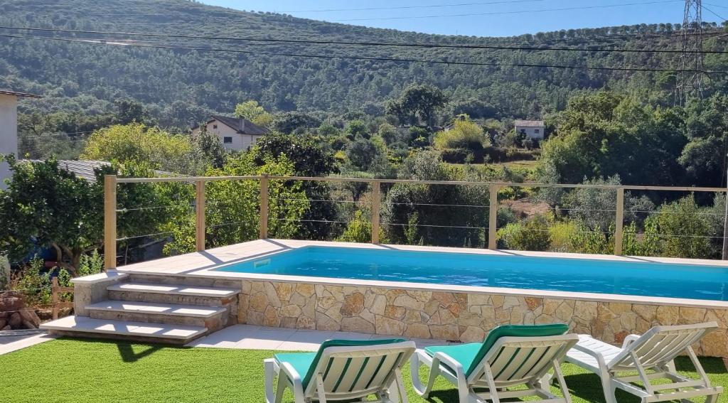 a swimming pool with two lawn chairs and a swimming pool at Casa Pregueira in Lisboinha