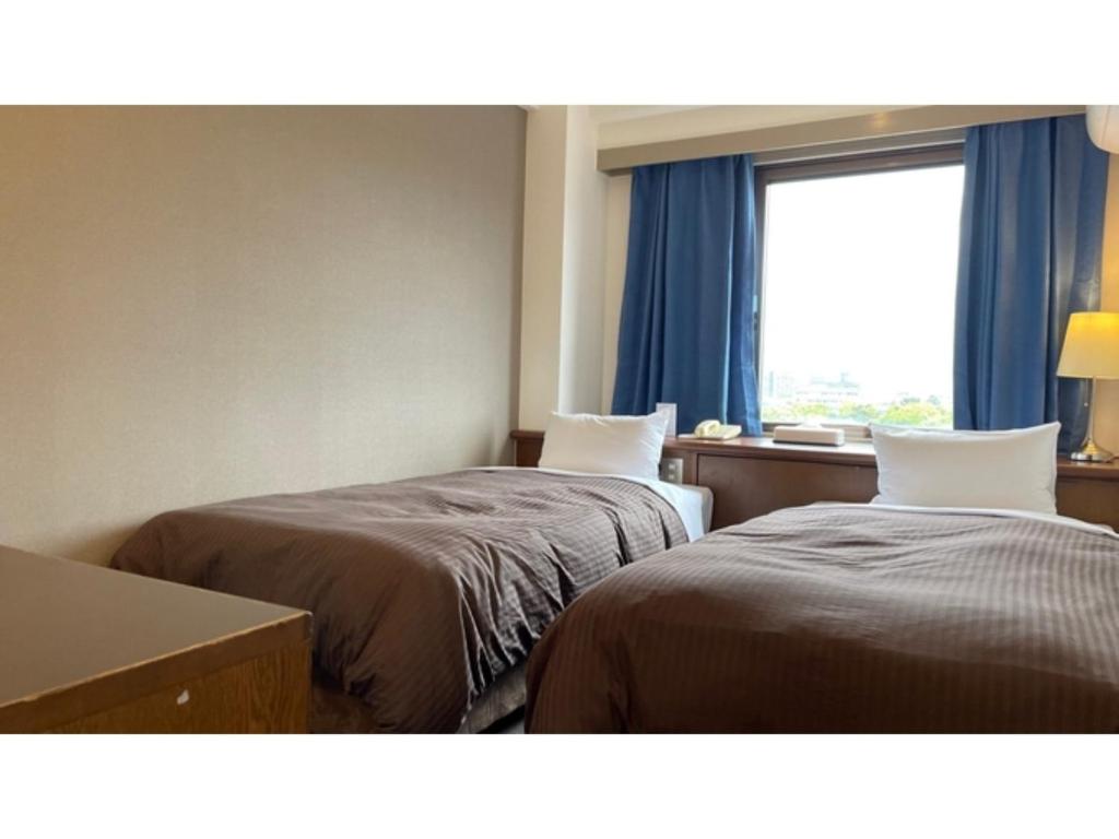 a hotel room with two beds and a window at Kanku Sun Plus Yutaka - Vacation STAY 38984v in Izumi-Sano
