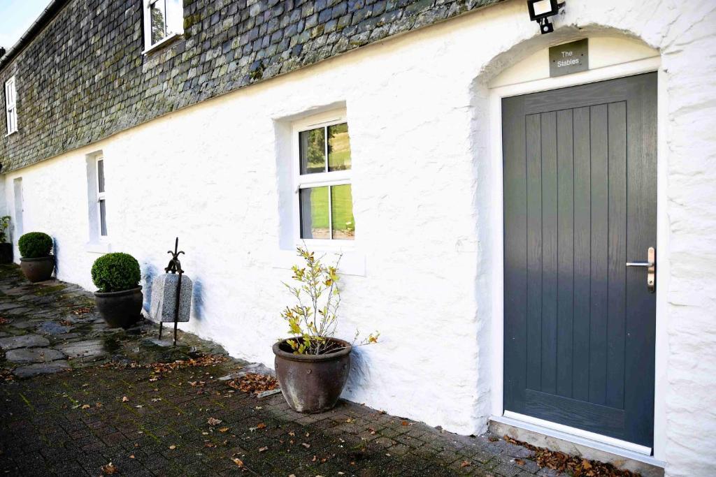 una casa blanca con una puerta negra y una planta en The Stables en Pitlochry