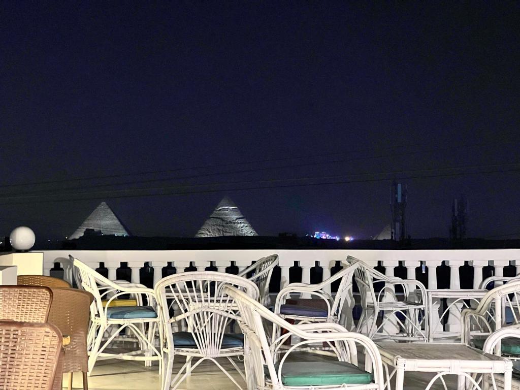 a group of white chairs sitting on a patio at night at Pyramids Gardens Hotel - فندق حدائق الاهرام in Cairo