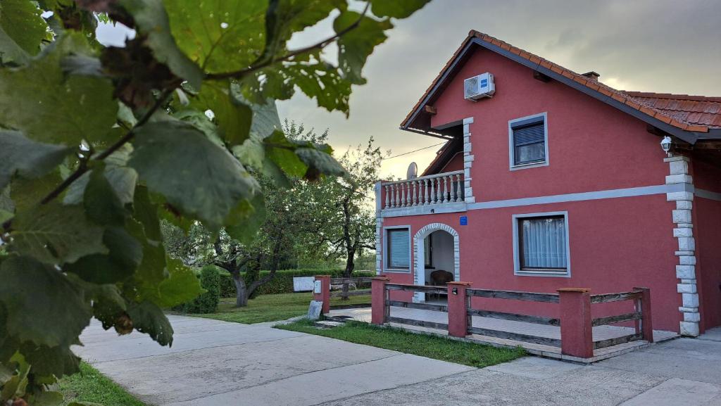 une maison rouge avec un balcon latéral dans l'établissement Apartment Asgard, à Drežnik Grad