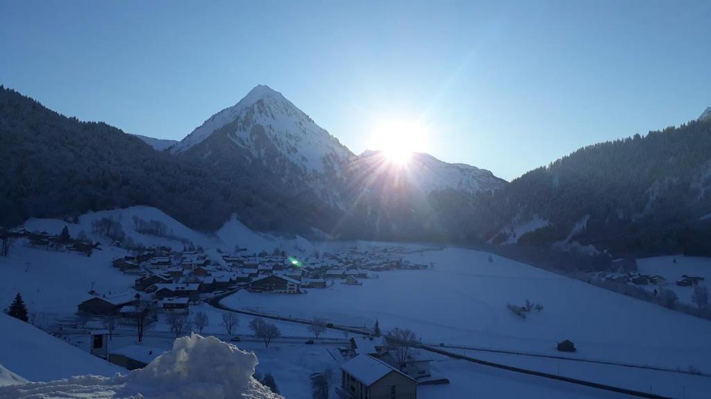 a view of a village in the mountains with the sun setting at Fernblick Frühstückspension in Schoppernau