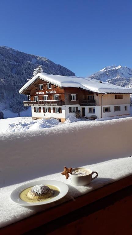 a plate of food and a cup of coffee in the snow at Fernblick Frühstückspension in Schoppernau