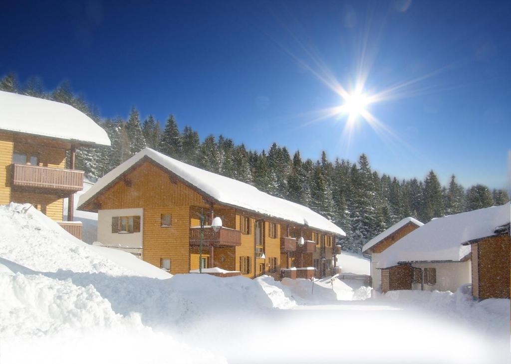 ein schneebedecktes Gebäude mit der Sonne dahinter in der Unterkunft Monarchia Park in Lachtal