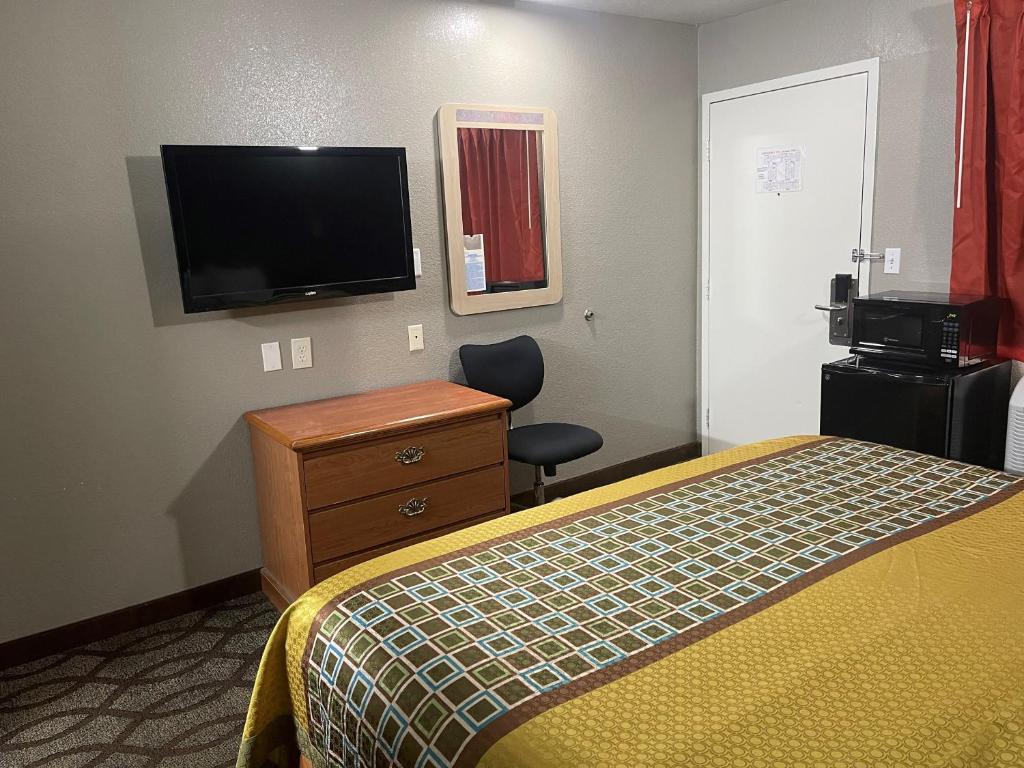 a hotel room with a bed and a flat screen tv at Super 7 Inn in Memphis