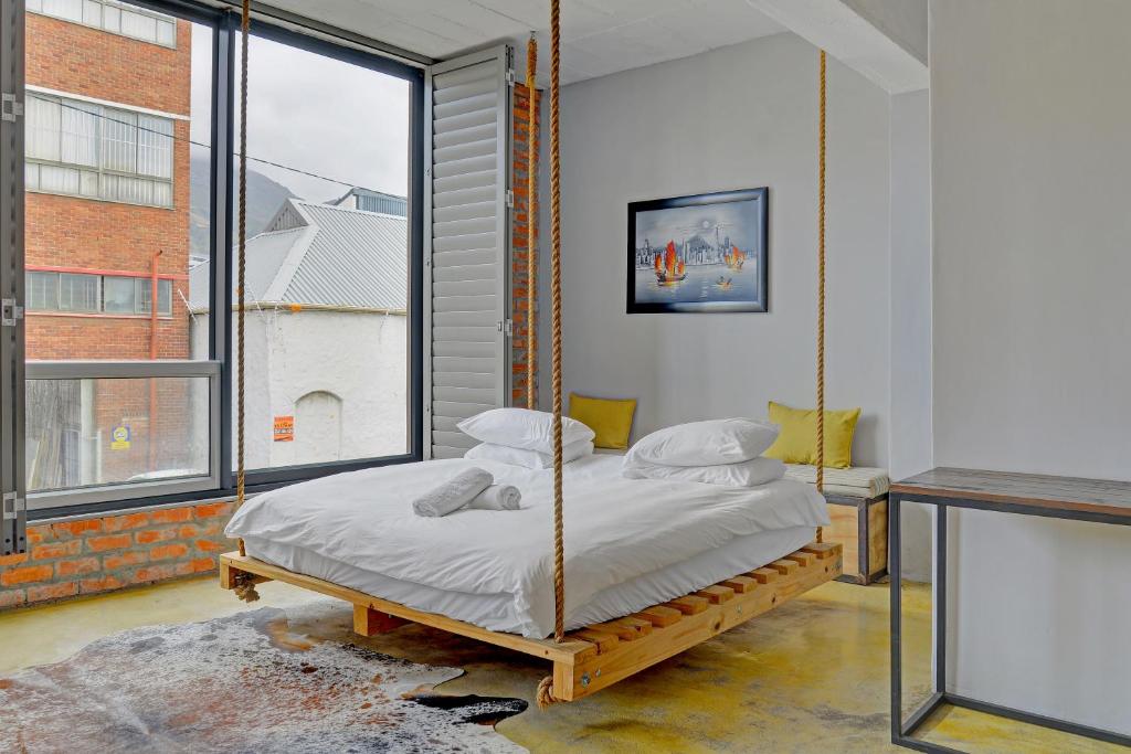 a swinging bed in a room with a large window at Harbour Views B101 in Cape Town