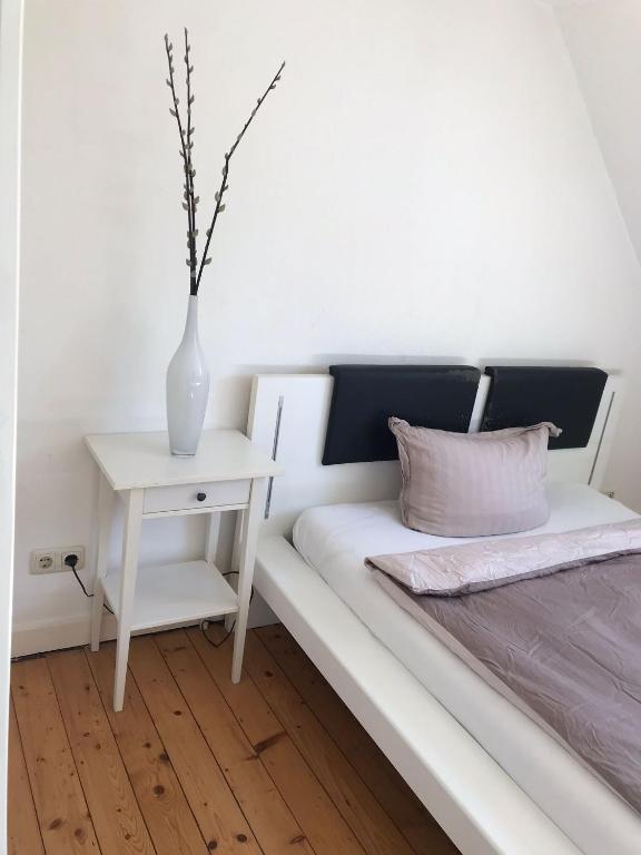 a white vase sitting on a bed next to a table at Maya's Place in Leverkusen