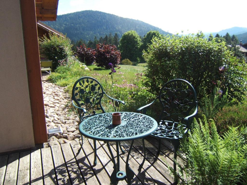 a table and chairs on a porch with a cup on it at B&B Chalet l'Epinette in Gérardmer