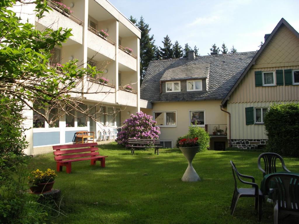 a yard with chairs and benches and a building at Pension Wölfel in Bad Steben