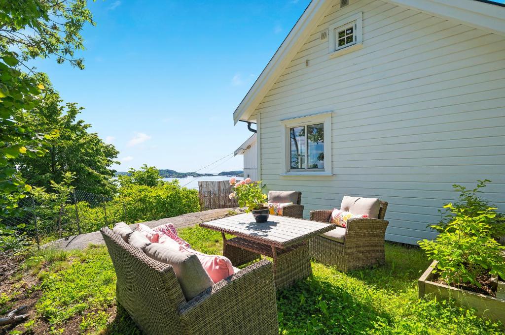 un patio con mesa y sillas frente a una casa en Kragerø hytte havsutsikt, en Kragerø