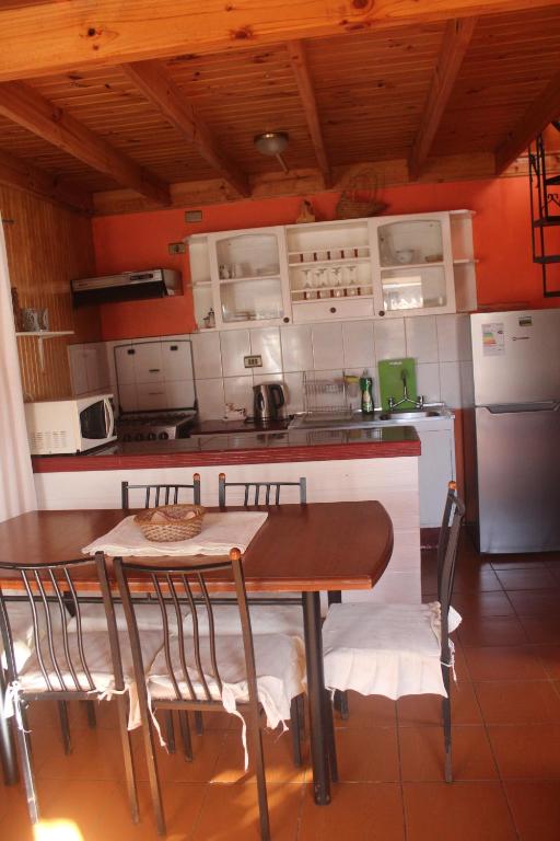 cocina con mesa, sillas y nevera en cabaña en Pichilemu, en Pichilemu