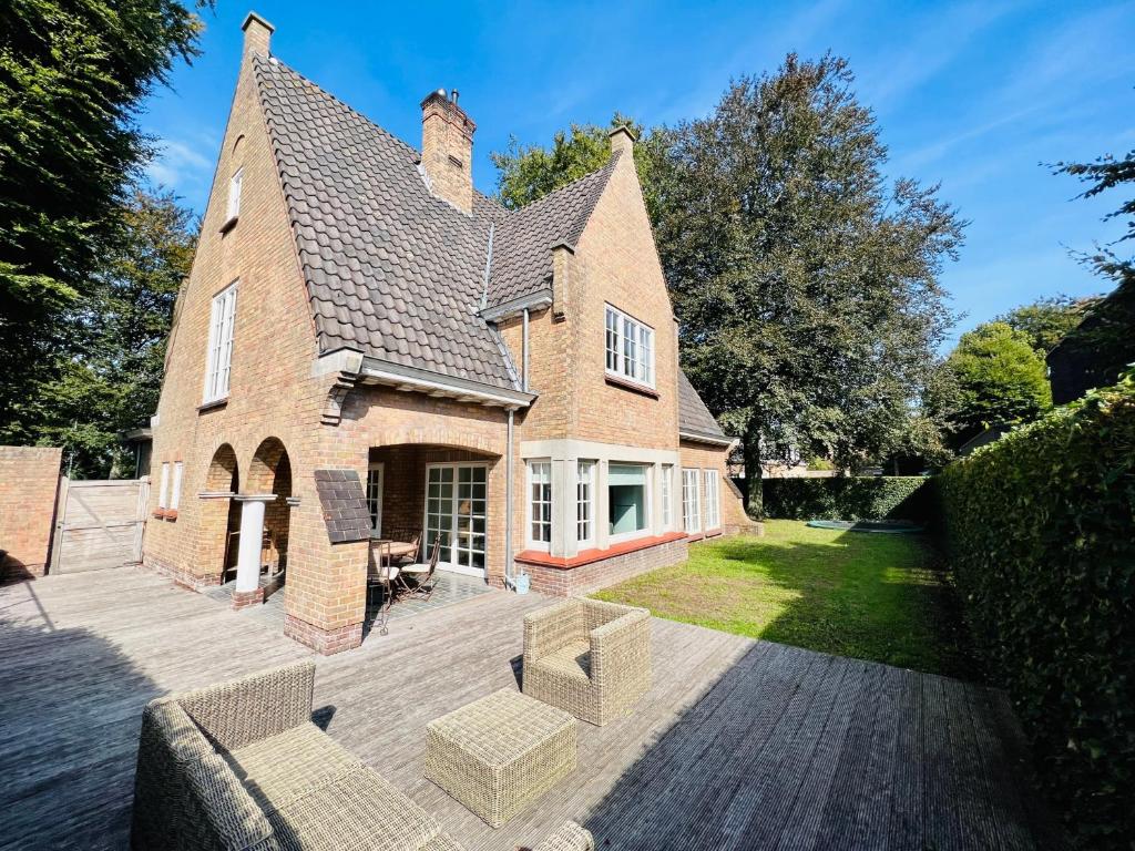 een groot bakstenen huis met een houten terras bij Le Coin Vert in Brugge