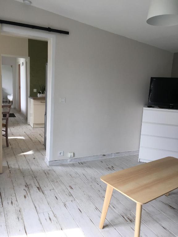 sala de estar con mesa y pared blanca en Charmant séjour à Andernos, en Andernos-les-Bains