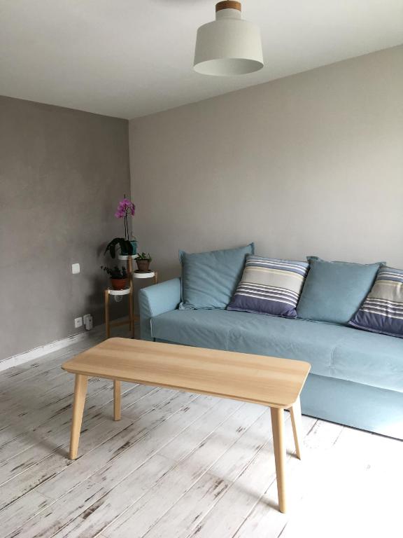 sala de estar con sofá azul y mesa de centro de madera en Charmant séjour à Andernos, en Andernos-les-Bains