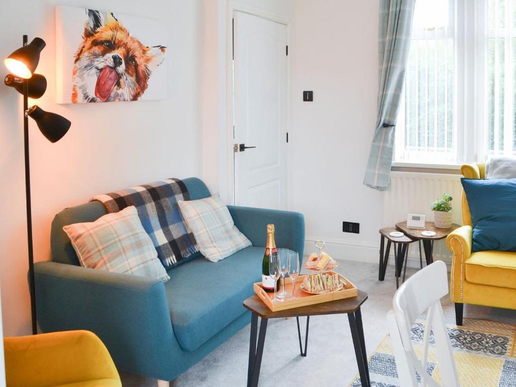 a living room with a blue couch and a table at Wellwood Cottage in Morpeth