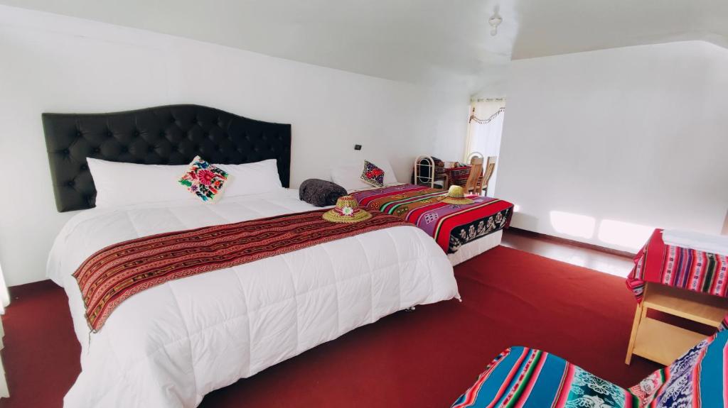 a bedroom with a large bed with a red carpet at Uros Utasa Lodge in Puno