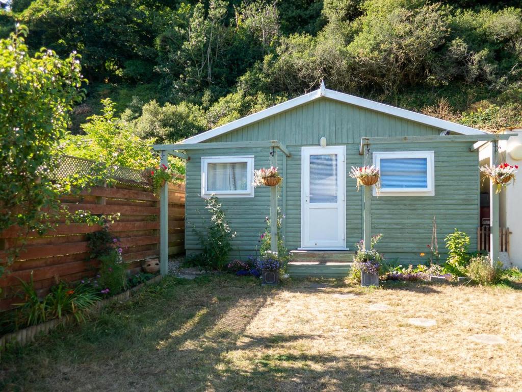 a small green house with a fence in a yard at The Chalet in Portreath