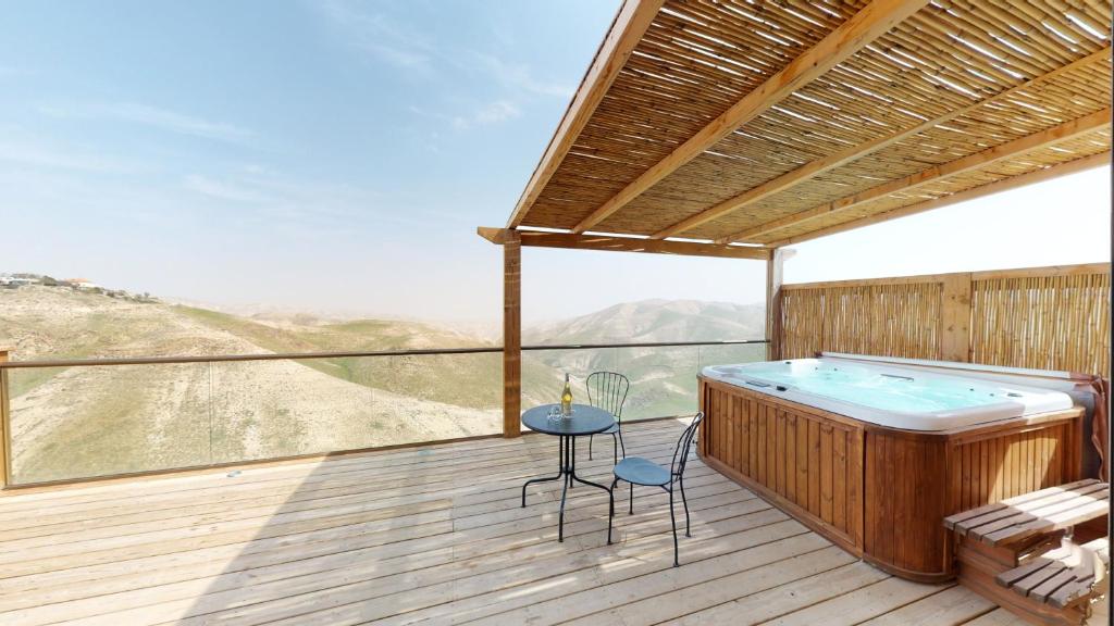 a hot tub on a deck with a table and chairs at Genesis Land Desert hospitality in Kfar Adumim