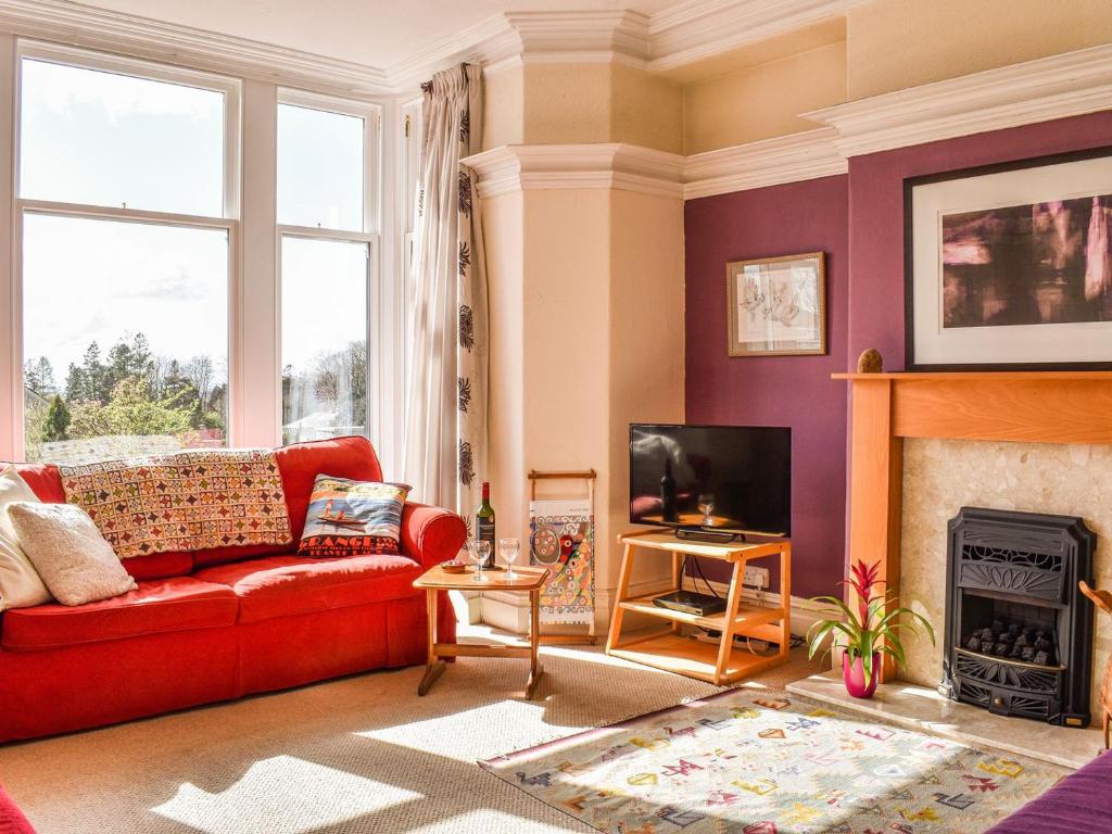 a living room with a red couch and a fireplace at Fell Mount in Grange Over Sands