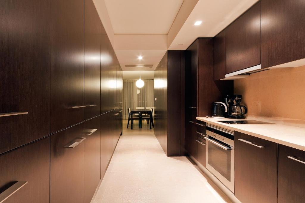 a kitchen with dark wood cabinets and a table at Troia Residence by The Editory - Apartamentos Marina in Troia