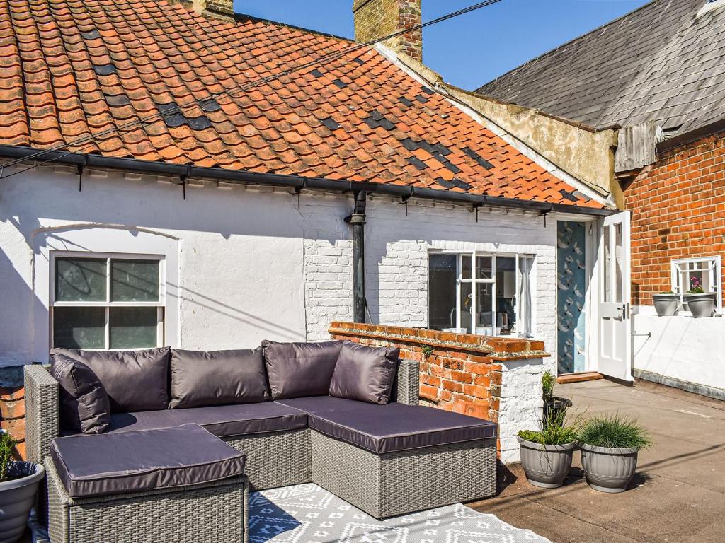 a couch sitting on a patio in front of a house at The Photographers House in Southwold