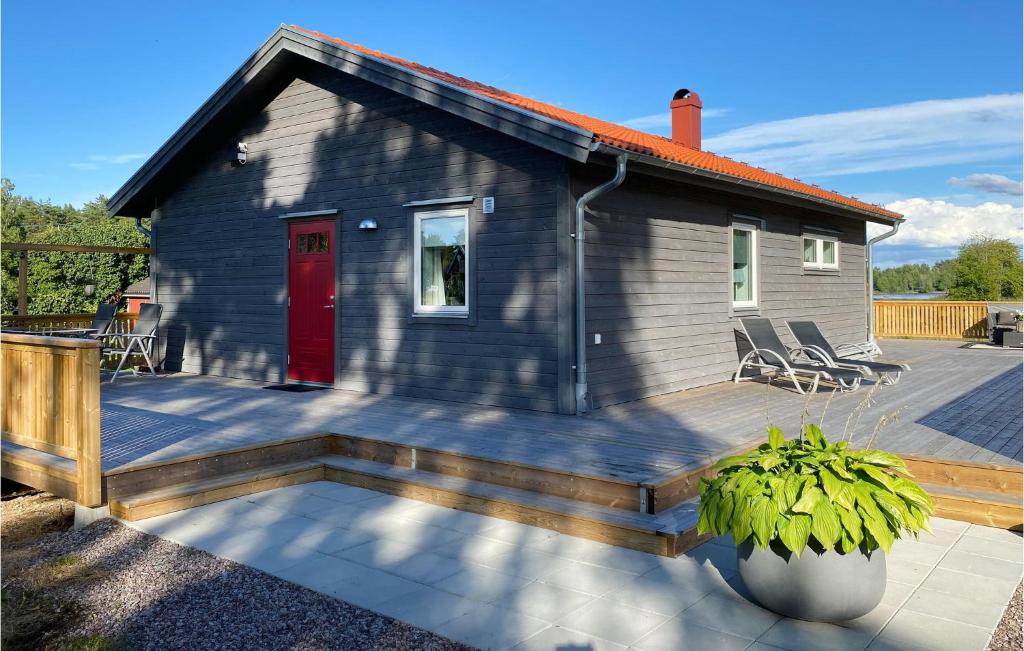 una pequeña casa con una puerta roja en una cubierta en Amazing Home In deshg With Internet And 3 Bedrooms, en Ödeshög