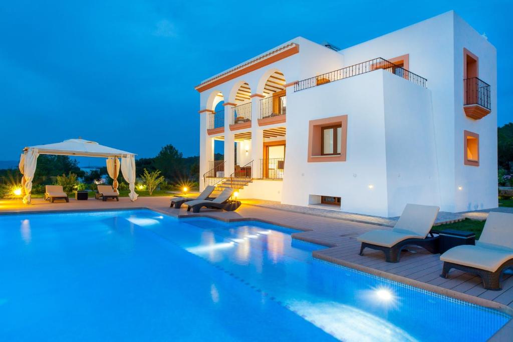 a villa with a swimming pool at night at Villa Benimussa in Ses Paisses