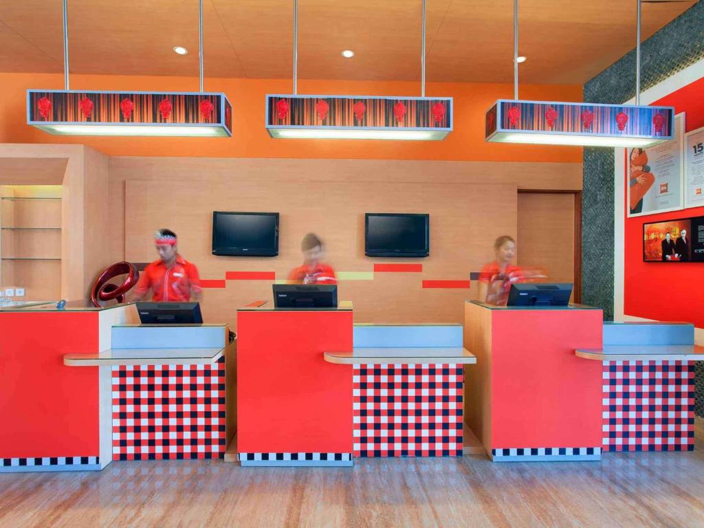 three people in a fast food restaurant with red counters at Ibis Bali Kuta in Kuta