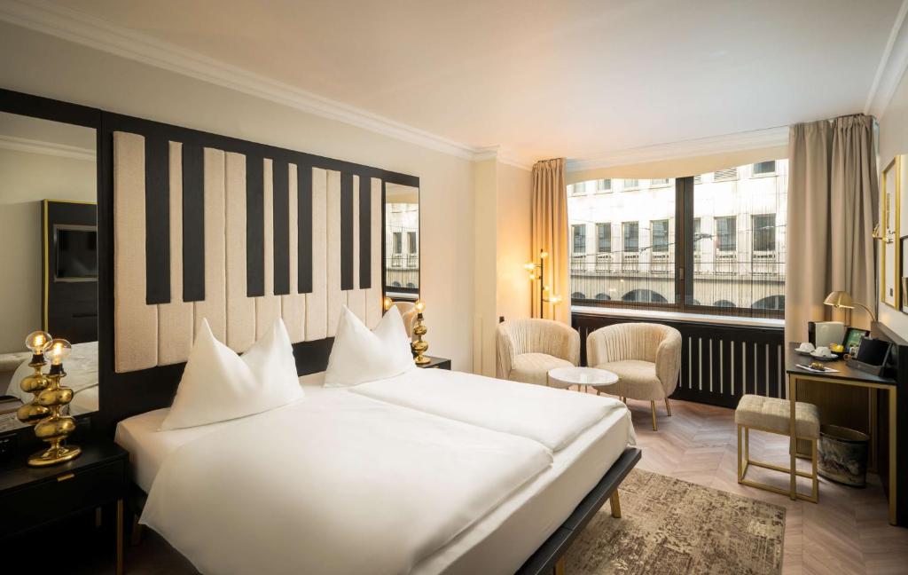a bedroom with a large white bed and a large window at elaya hotel vienna city center in Vienna