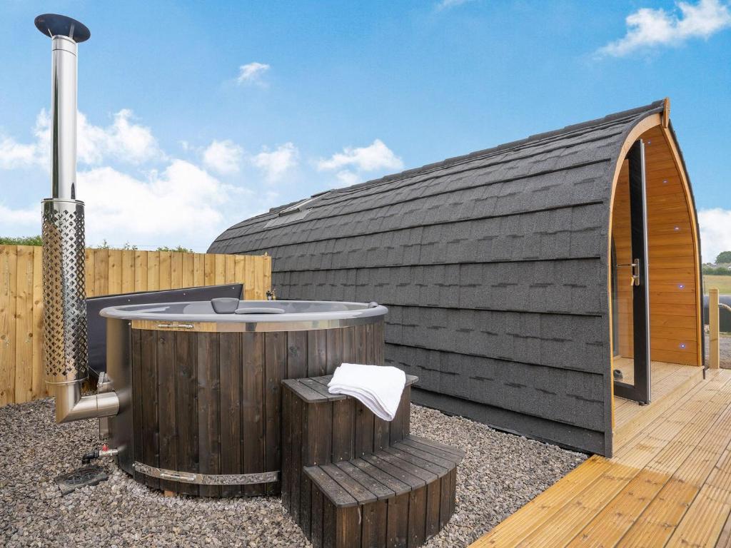 a hot tub sitting next to a wooden building at Barcud- UK37574 in Llanboidy