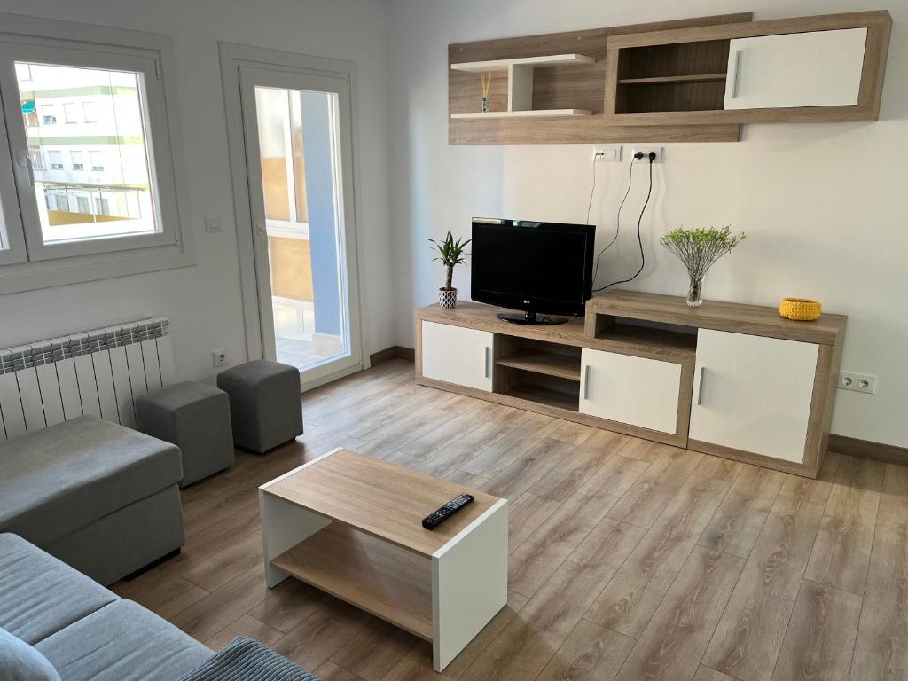 sala de estar con sofá y TV de pantalla plana en Apartamento vacacional en Redondela